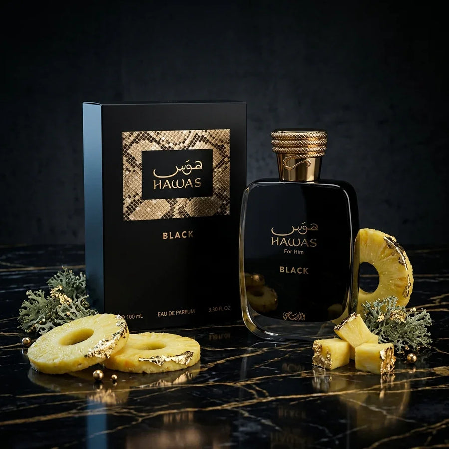 Hawas Black perfume for men with gold-accented bottle, box, and pineapple slices on marble
