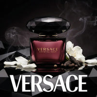 Versace Crystal Noir perfume bottle with white flower petals and spices on a black background