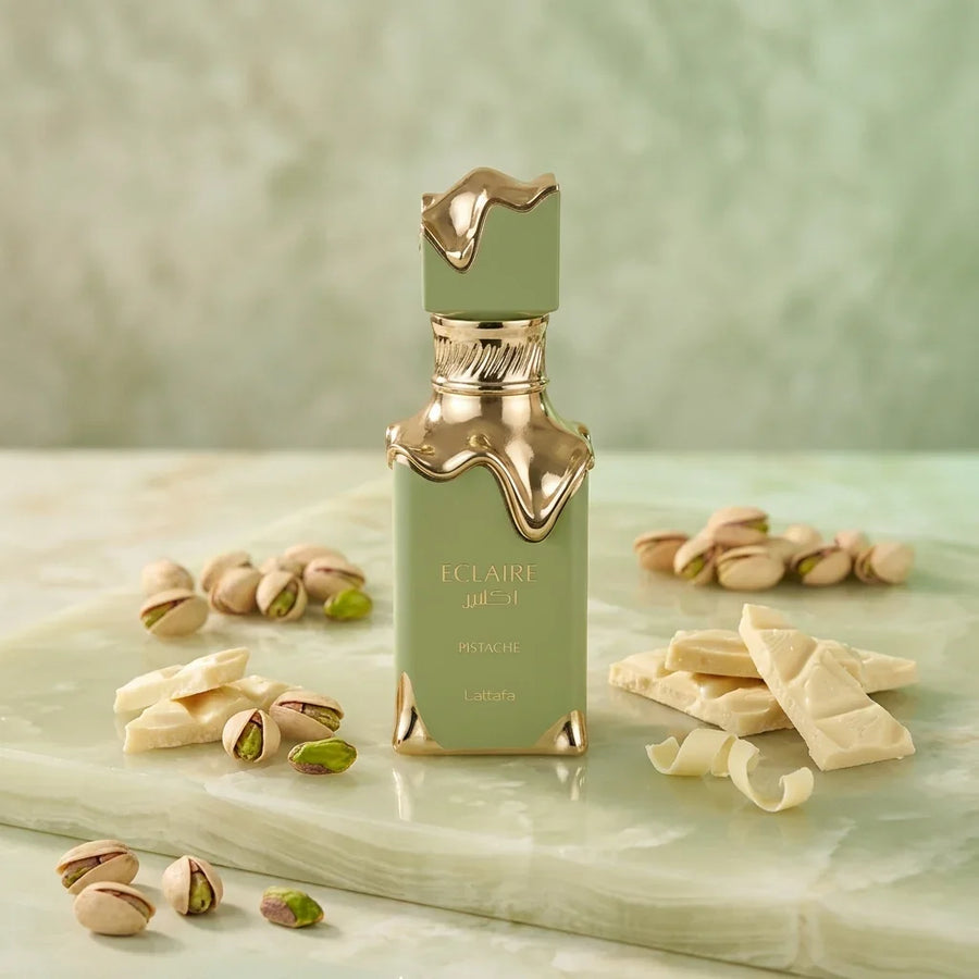 Green and gold Eclaire Pistache perfume bottle with pistachios and white chocolate on marble