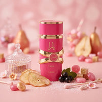 Lattafa Yara perfume in a pink and gold bottle surrounded by pear, berries, and sweets