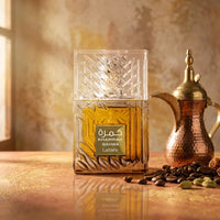 Lattafa Khamrah Qahwa perfume bottle with coffee beans and a traditional coffee pot on a table