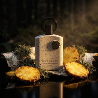 Supremacy Collector's Edition perfume bottle with pineapples, birch bark, and greenery
