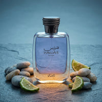 Hawas For Him perfume bottle with purple liquid, surrounded by lime slices and pebbles on stone surface