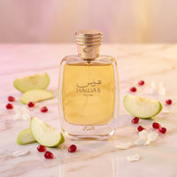 Hawas For Her perfume bottle with apple slices, pomegranate seeds, and white flowers on marble